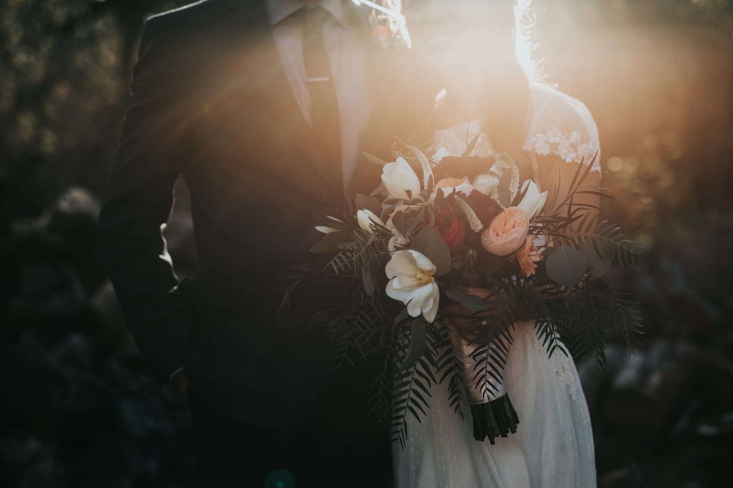 Couple holding a floral bouquet in warm golden light